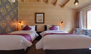 A hotel room with two beds, wooden walls, a framed picture on the wall, and a window with curtains. - Treebo Premium Blue Mountain Country Club And Resort (Siliguri)