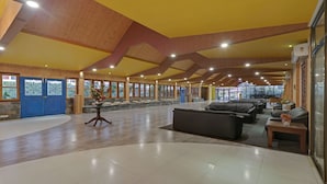 A spacious lobby with a high ceiling, large windows, and a seating area with sofas. - Treebo Premium Blue Mountain Country Club And Resort (Siliguri)