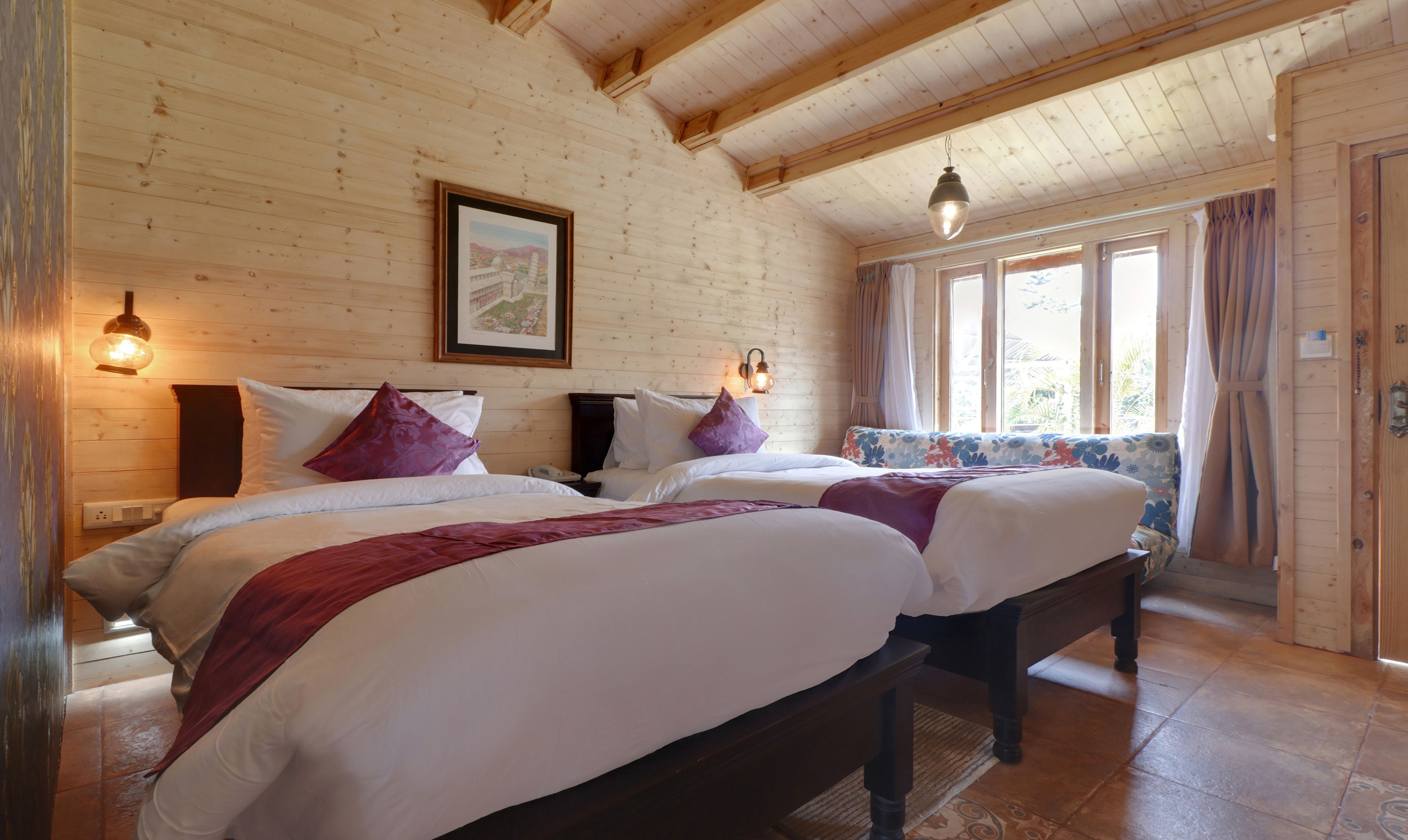 Una habitación tipo cabaña de madera con dos camas, un banco y una ventana con cortinas.