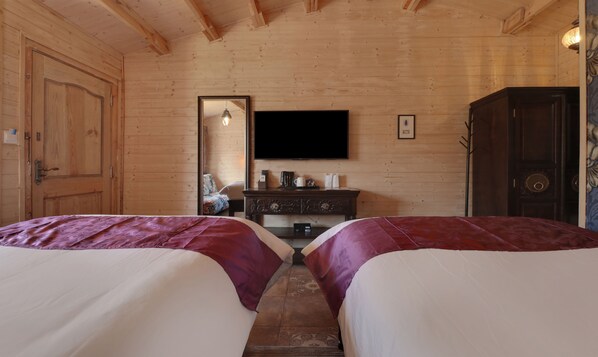 Una habitación de madera con dos camas, un aparador, un televisor y un espejo.