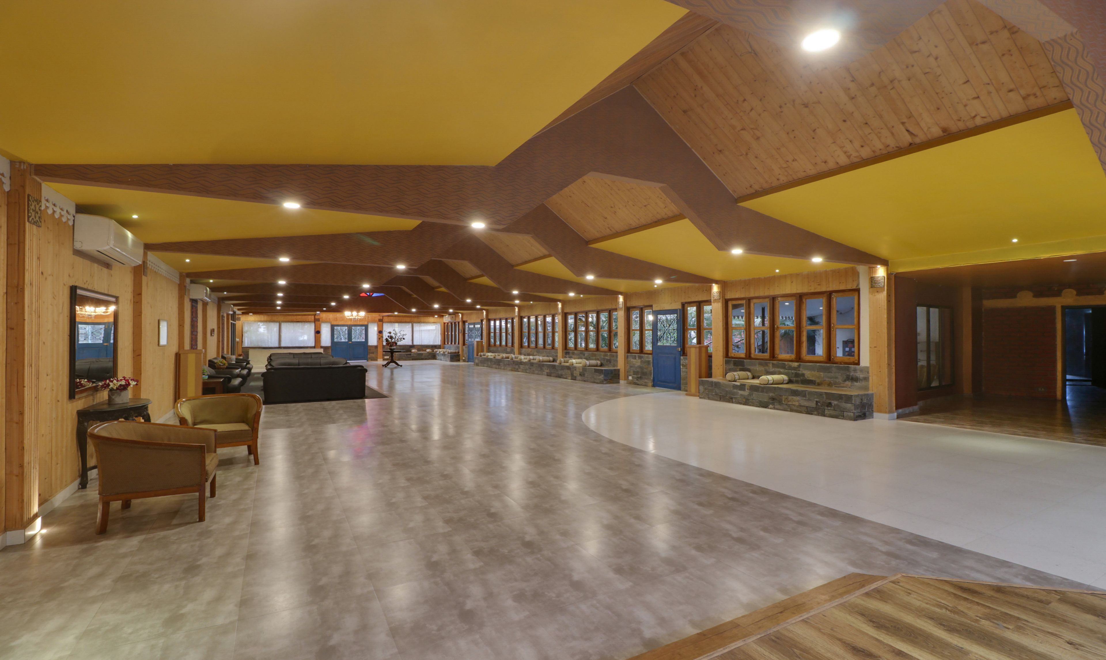 Un vestíbulo amplio con techo alto, vigas de madera y una zona de estar grande con sofás y sillones.