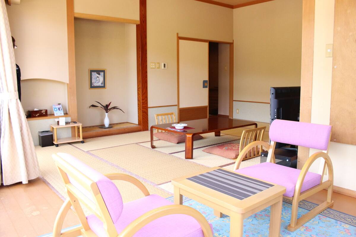Una habitación al estilo japonés tradicional con suelo de tatami, una mesa de madera baja y sillas a juego.