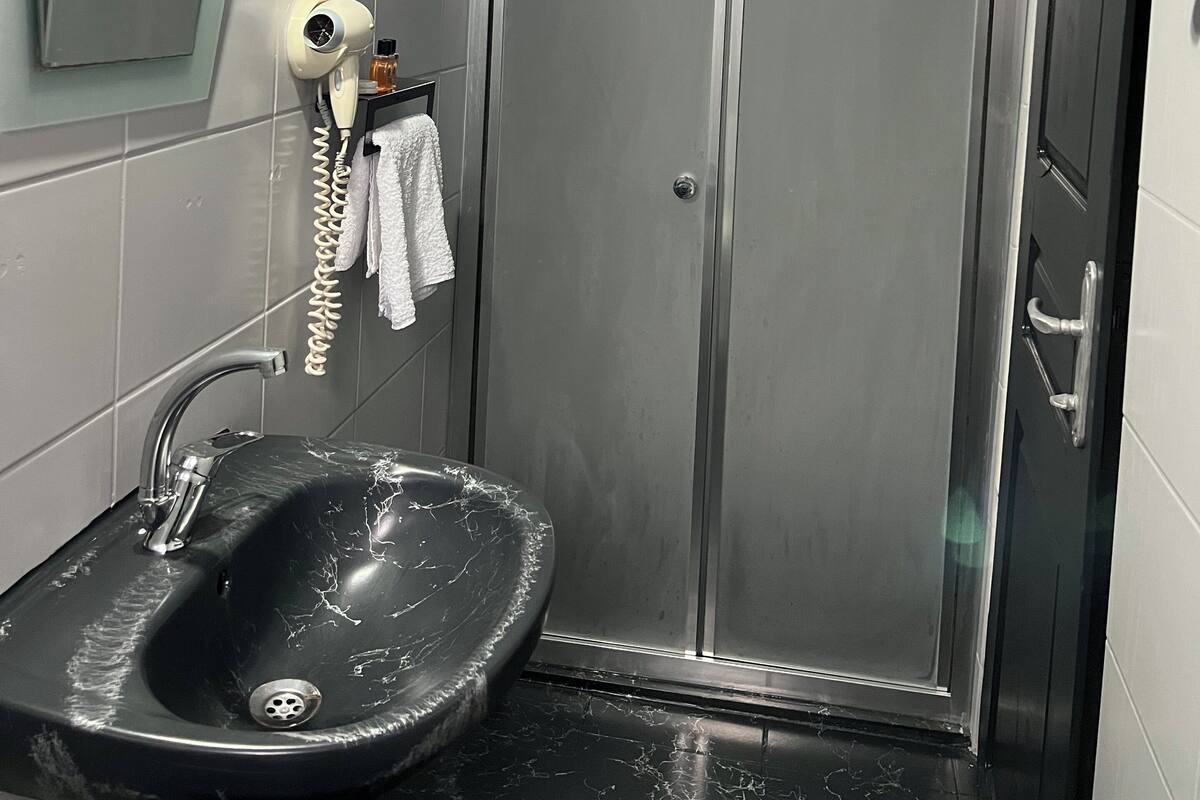 Casa de banho com lavatório, secador de cabelo e cabine de duche.