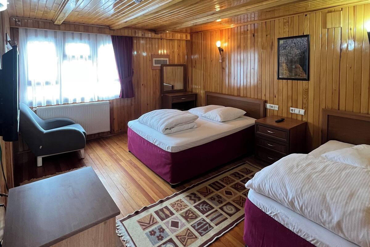 Quarto com painéis de madeira, duas camas, uma escrivaninha e uma cadeira.