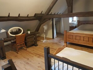 A bedroom with a wooden bed, a desk with a mirror, and a chair.