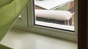 Une fenêtre donnant sur un bâtiment recouvert de neige.