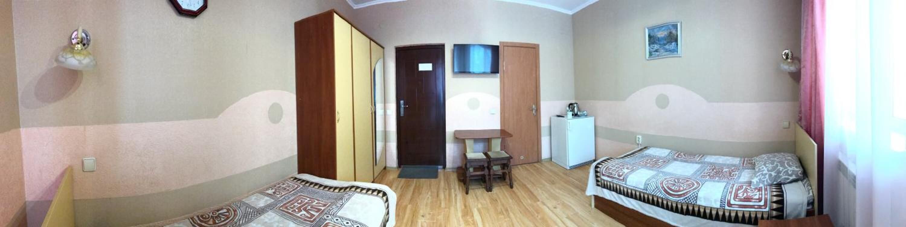 Een hotelkamer met twee bedden, een bureau, een televisie en een deur naar een andere kamer.