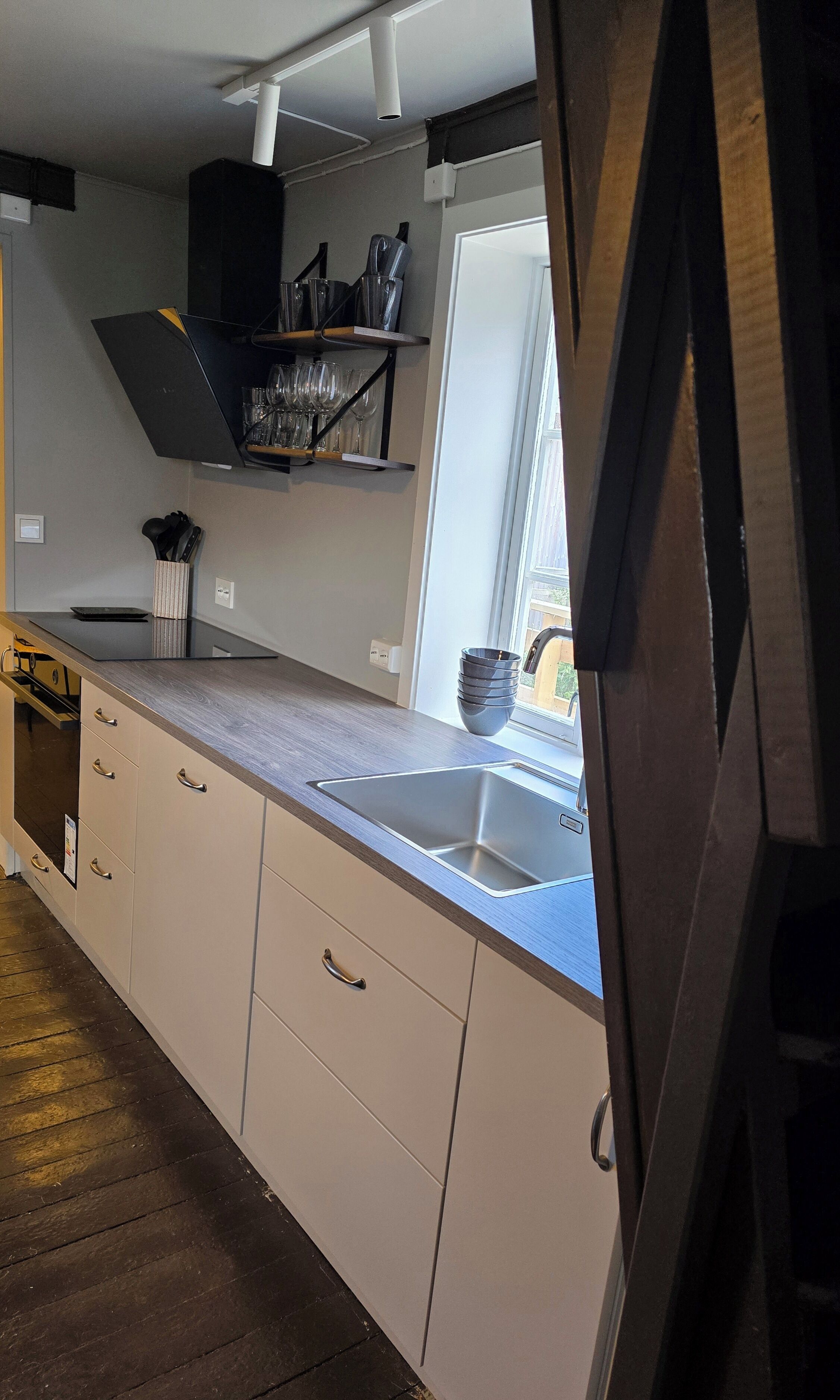 Una cocina moderna con un lavaplatos integrado, armarios de madera y una ventana con vistas a un balcón.