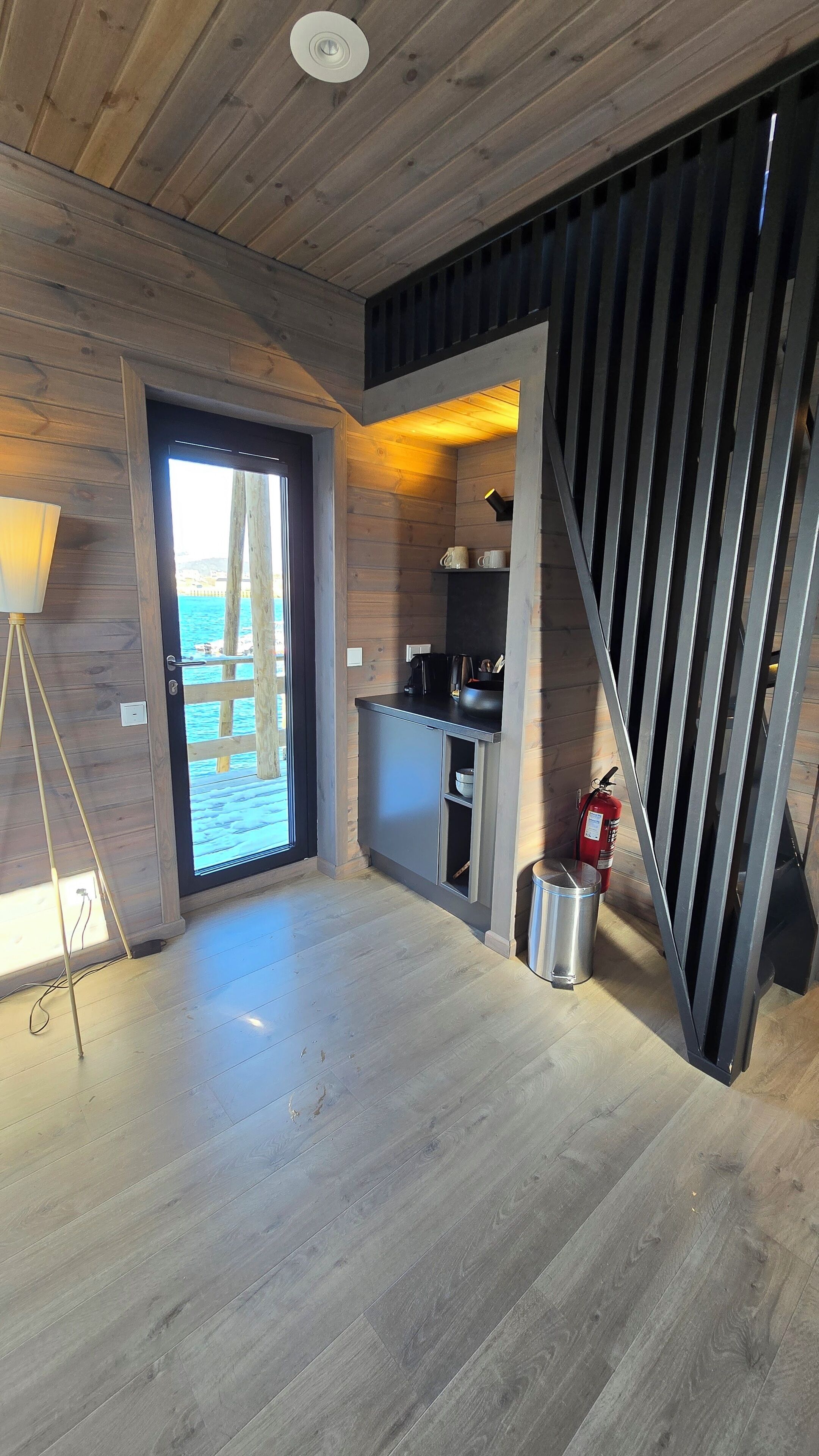 A wooden interior with a kitchen area, a door leading outside, and a fire extinguisher.