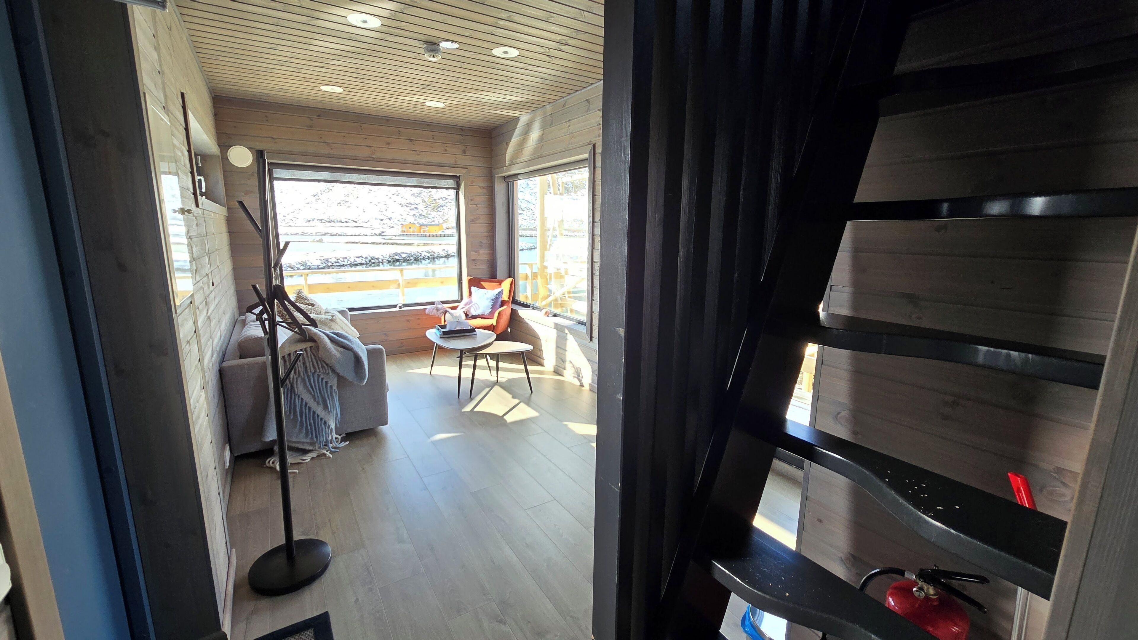 A modern interior with a wooden ceiling, a sofa, a chair, and a small table.