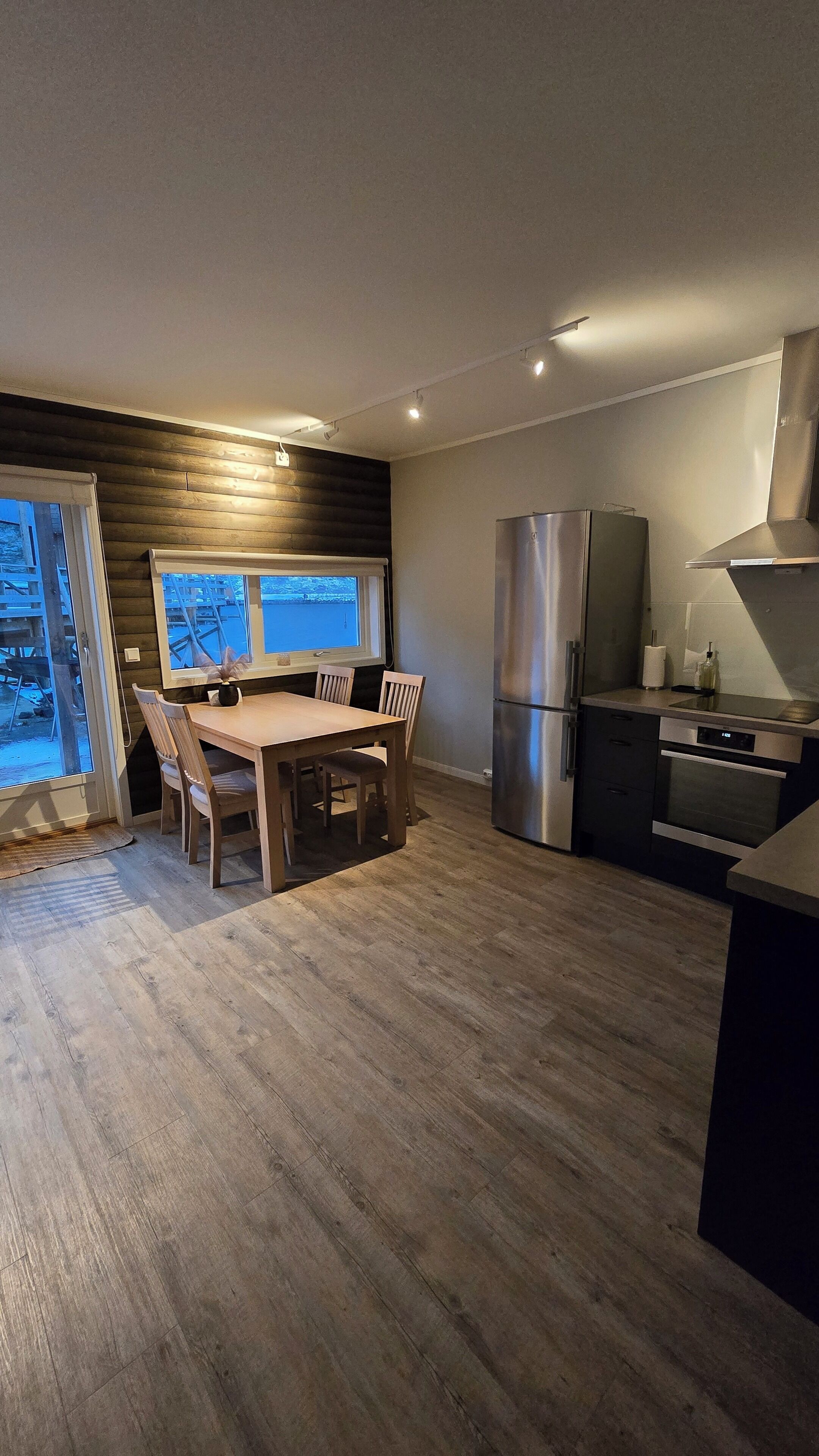 Eine moderne Küche mit Essbereich, Holzboden und Blick durch das Fenster.