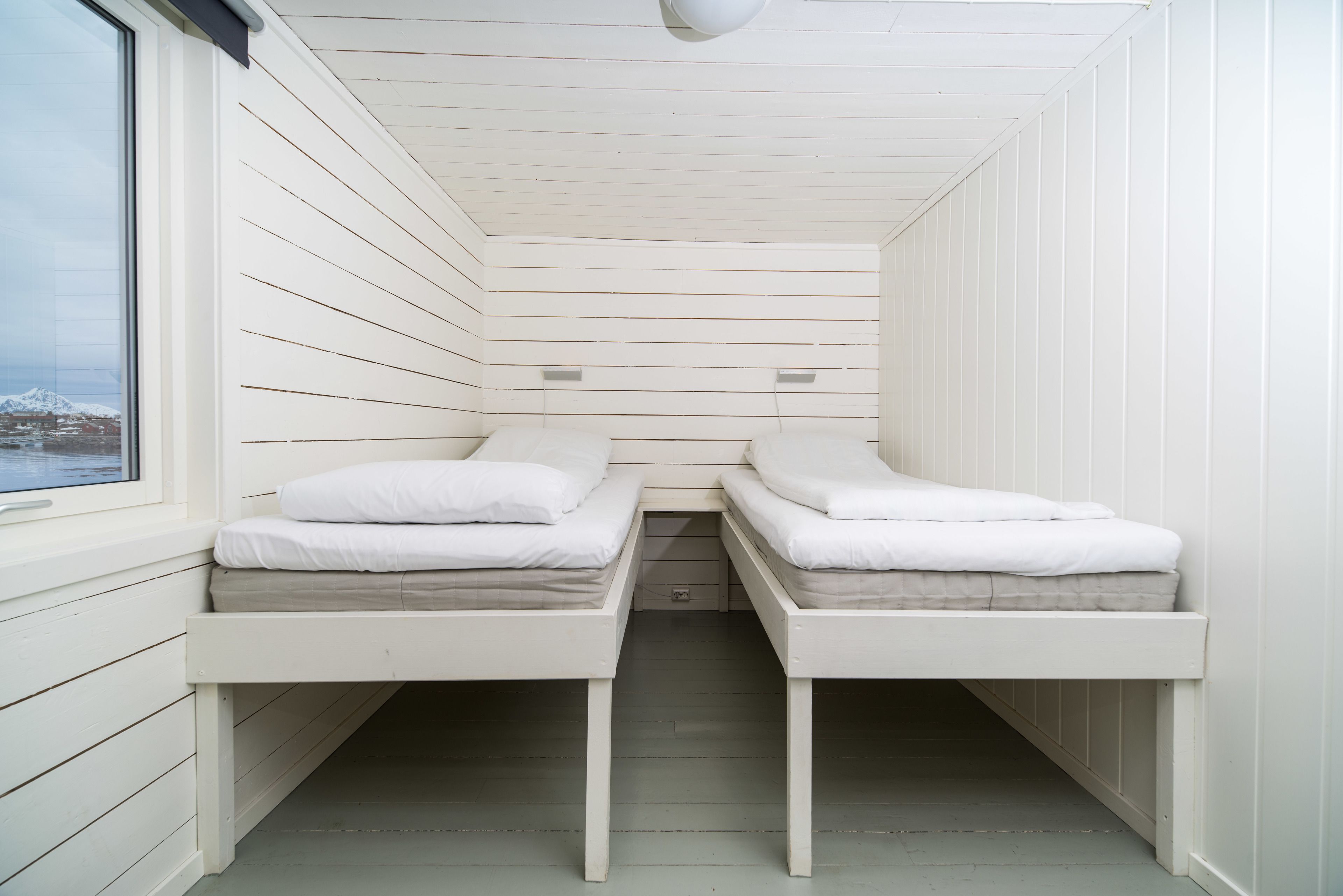 Habitación compacta con dos literas, una ventana y vista a un paisaje nevado.