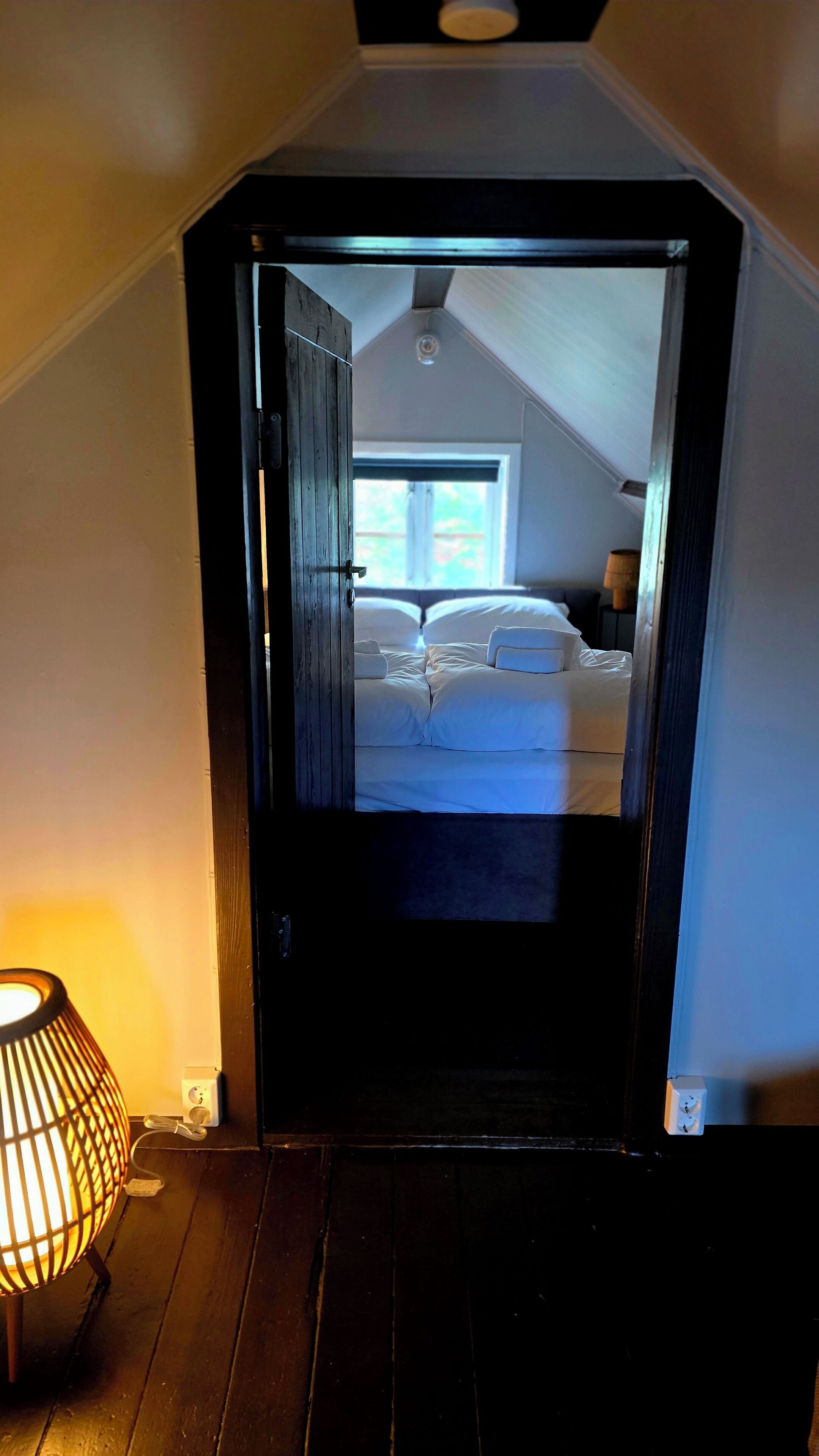 A room with a bed, a lamp, and a window.