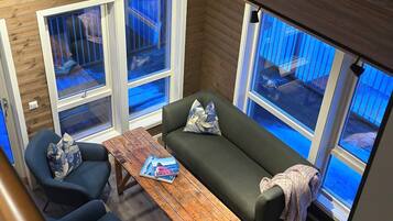Ein modernes Interieur mit Holzboden, einem grünen Sofa, blauen Sesseln und einem Couchtisch aus Holz.