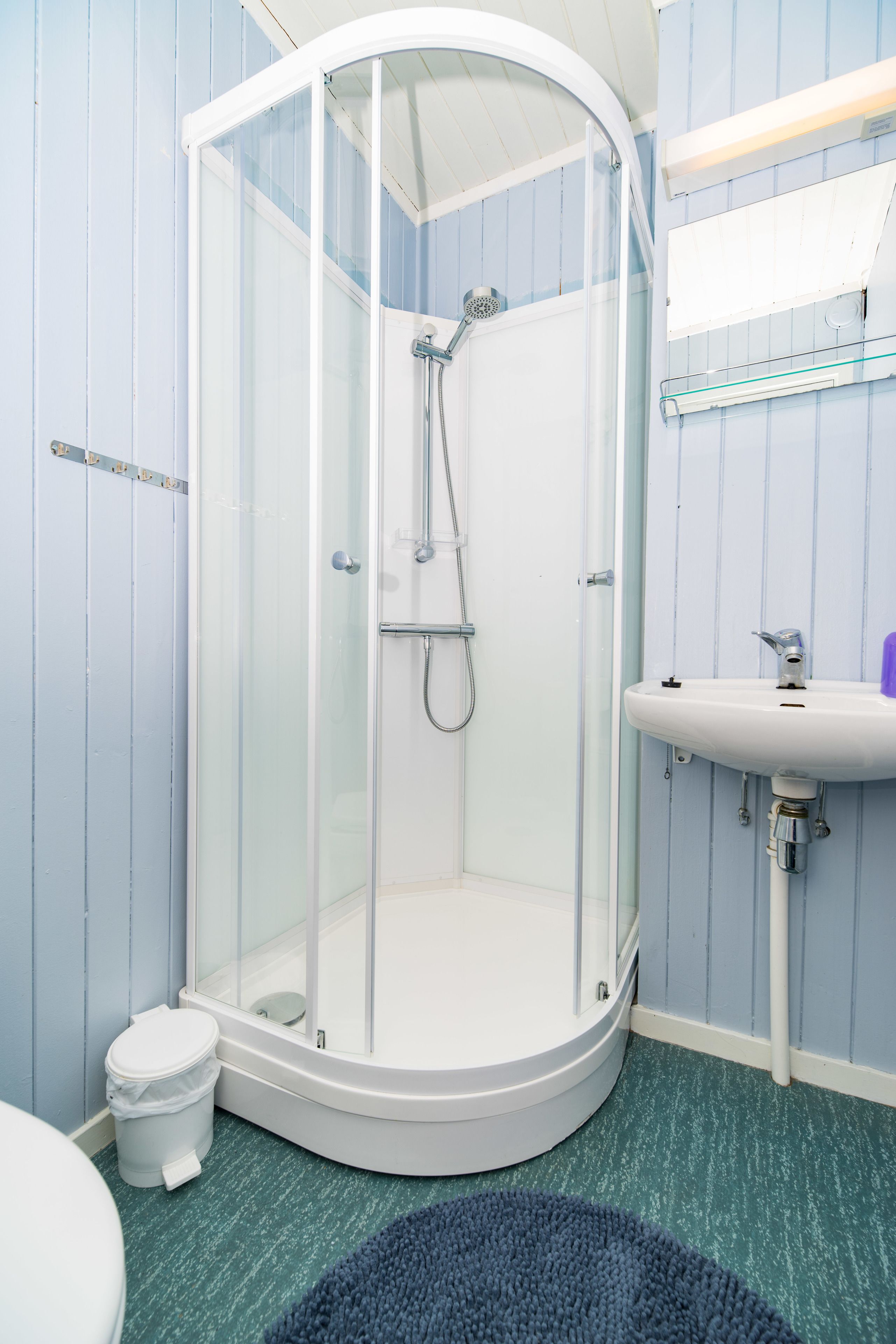 Eine Dusche mit Glastür, ein weißes Waschbecken und ein blaues, strukturiertes Badezimmer