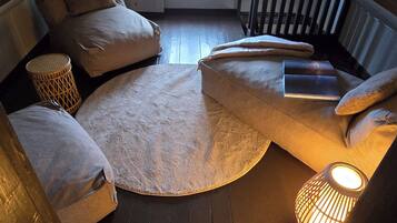 A loft bedroom with a sloped ceiling, a window, a circular rug, and a small lamp.