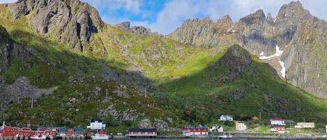 Un puerto deportivo con varias embarcaciones amarradas, un telón de fondo montañoso y un cielo despejado.