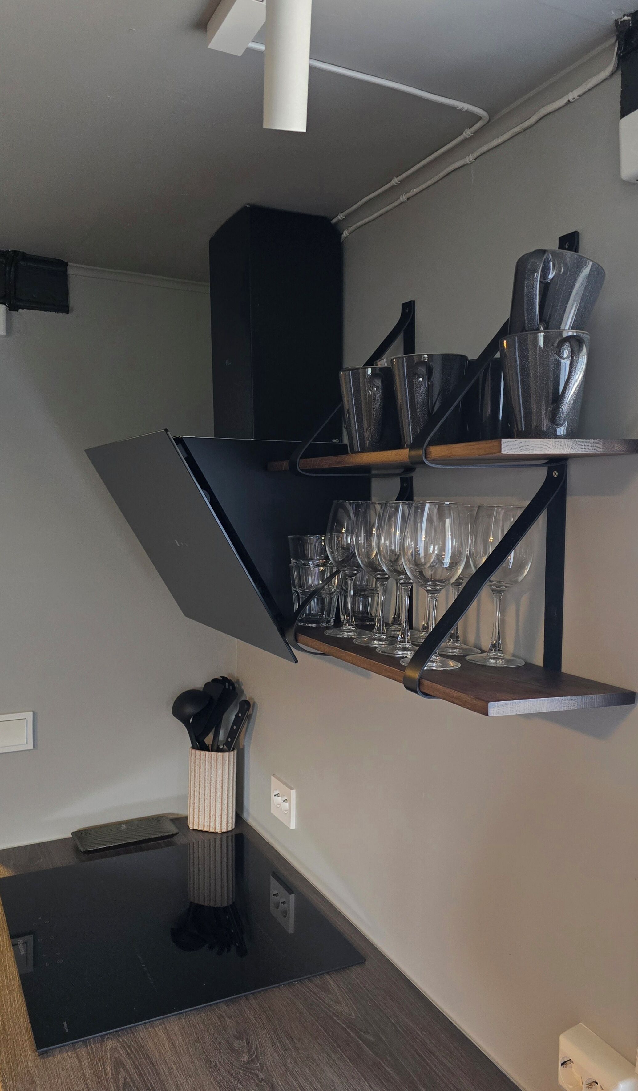 Una cocina moderna con encimera negra, estante empotrado para vinos y estufa negra.