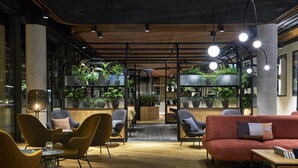 A modern lounge area with seating, plants, and a wooden floor. - PURO Łódź Centrum (Lodz)
