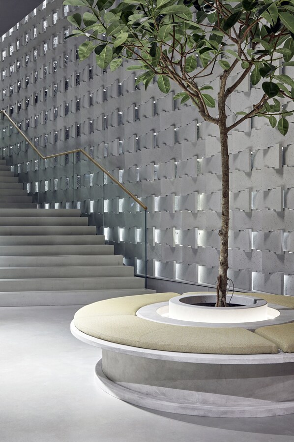 A staircase with a modern design, a tree planter with a tree, and a circular seating area.