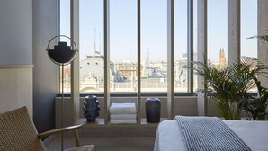 A hotel room with a large window, a bed, a chair, a vase, and a plant. - PURO Łódź Centrum (Lodz)