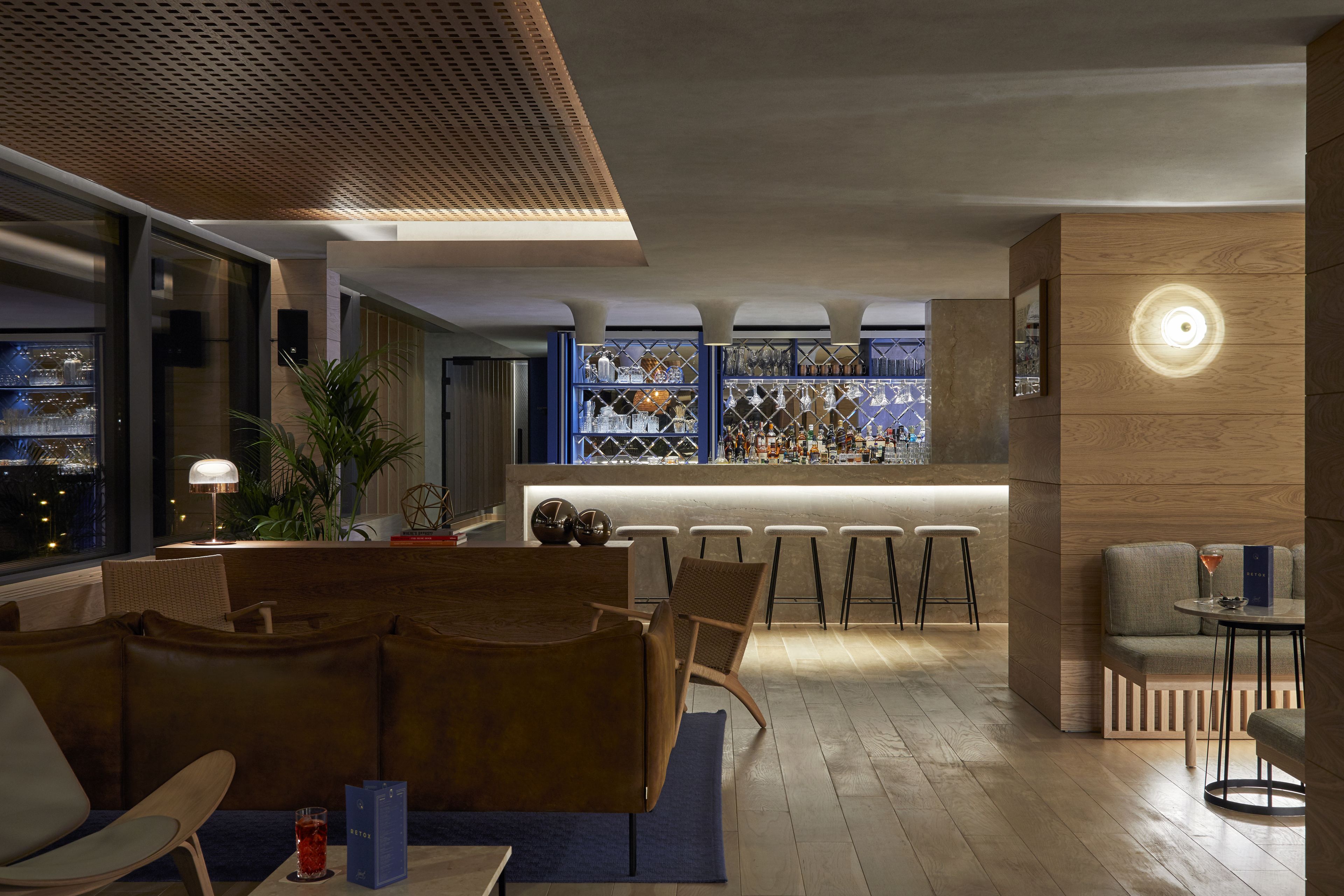 A modern bar area with seating, a bar counter, and shelves of glassware.