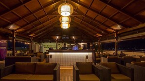 Zona de bar al aire libre con mobiliario de mimbre y barra.