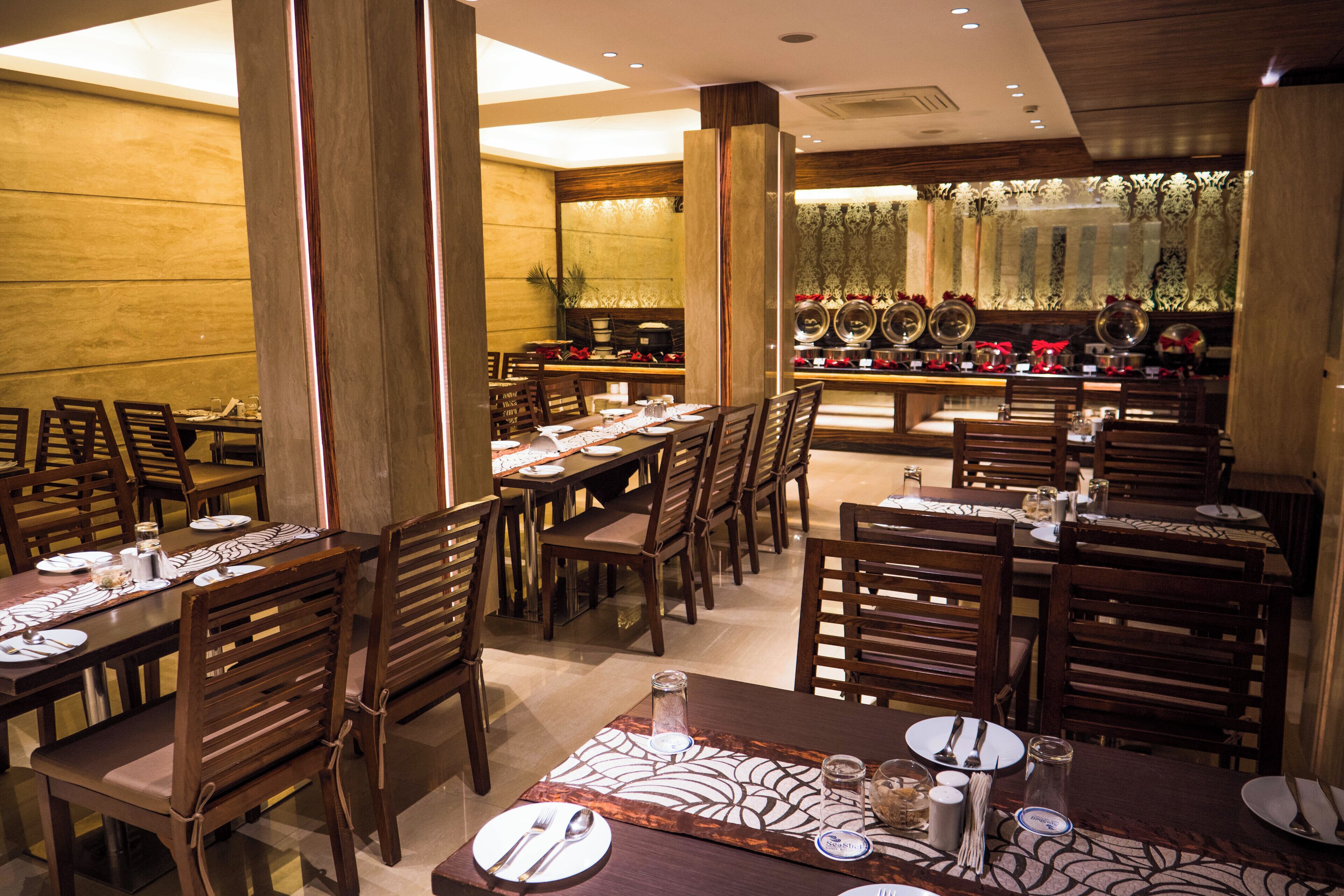 A restaurant with multiple dining tables and chairs, each set with plates, cutlery, and glasses.