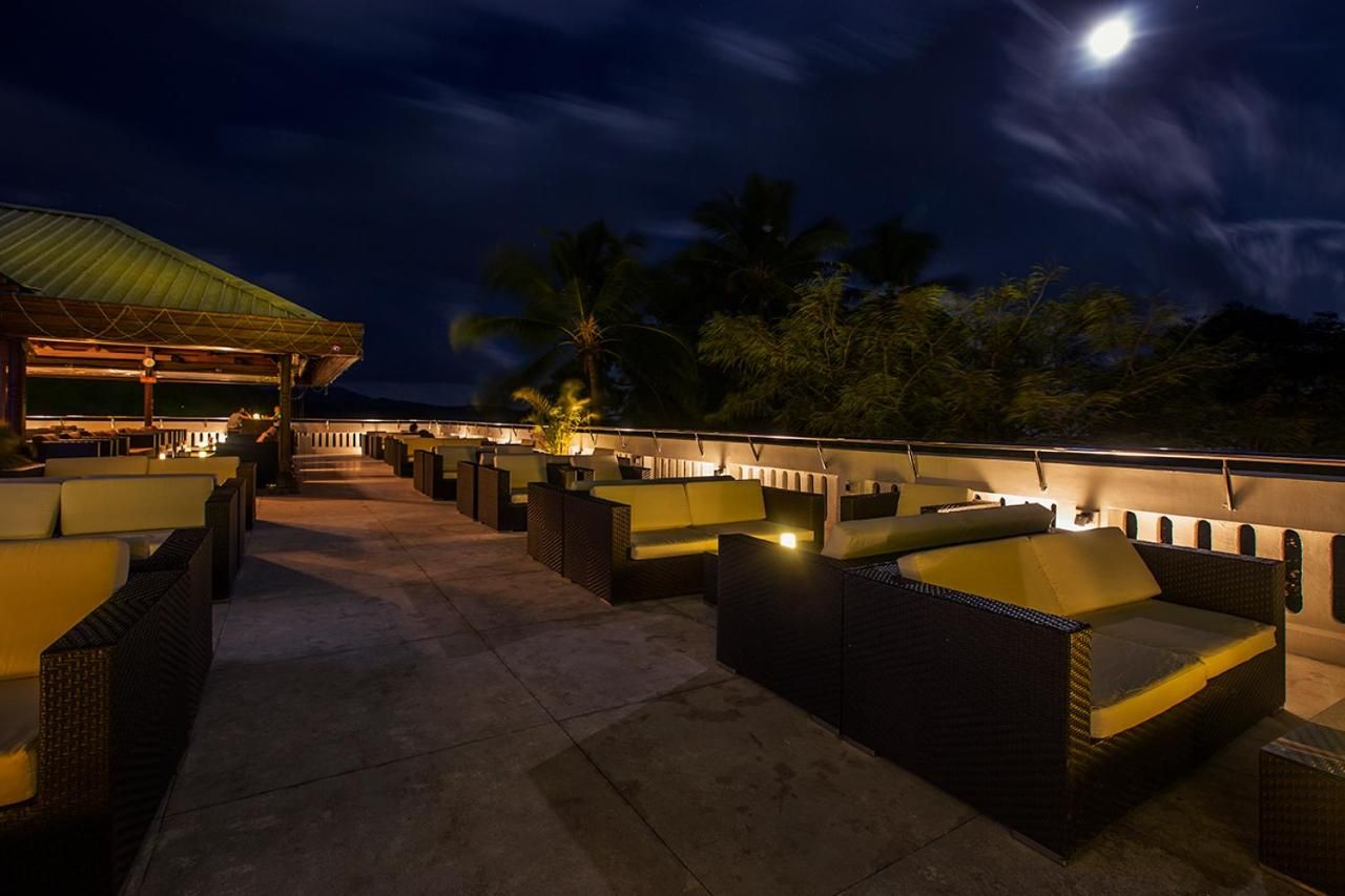 An outdoor seating area with wicker furniture and a covered section, under a night sky with a visible moon.