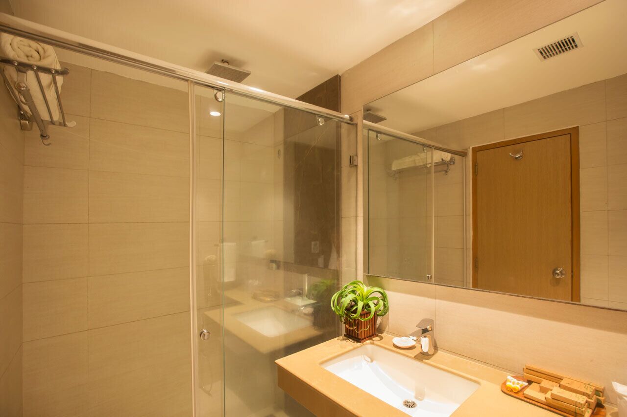 Un baño moderno con cabina de ducha de vidrio, un lavabo con espejo y una puerta de madera.