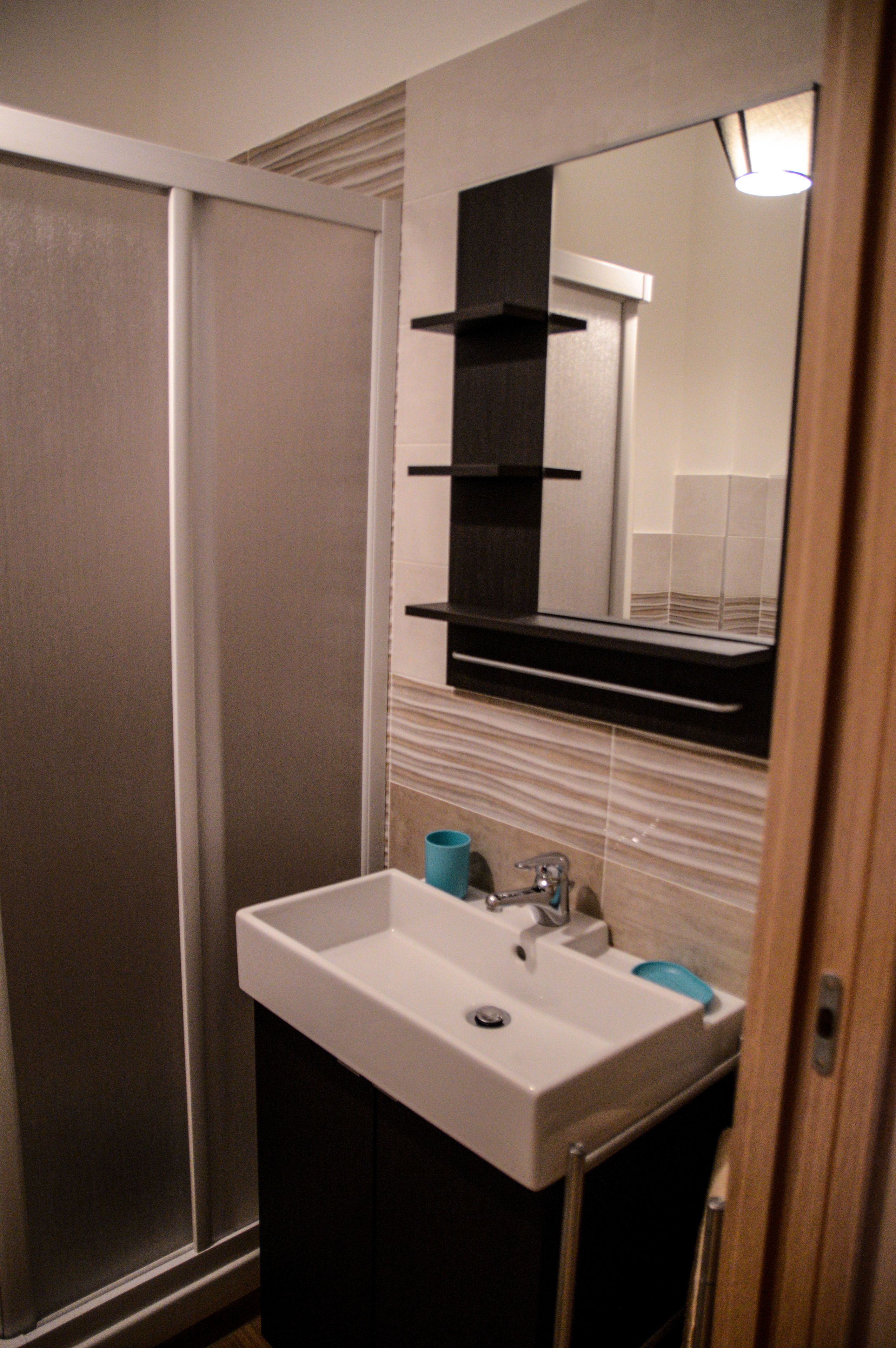 A bathroom with a white sink, a mirror, and a towel rack.