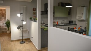A modern kitchen with green cabinets, a dining area with a table and chairs, and a floor lamp. - La Fara B&B (Benevento)