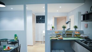 A modern kitchen with a dining area, featuring a central island with food items, a built-in stove, and a seating arrangement. - La Fara B&B (Benevento)