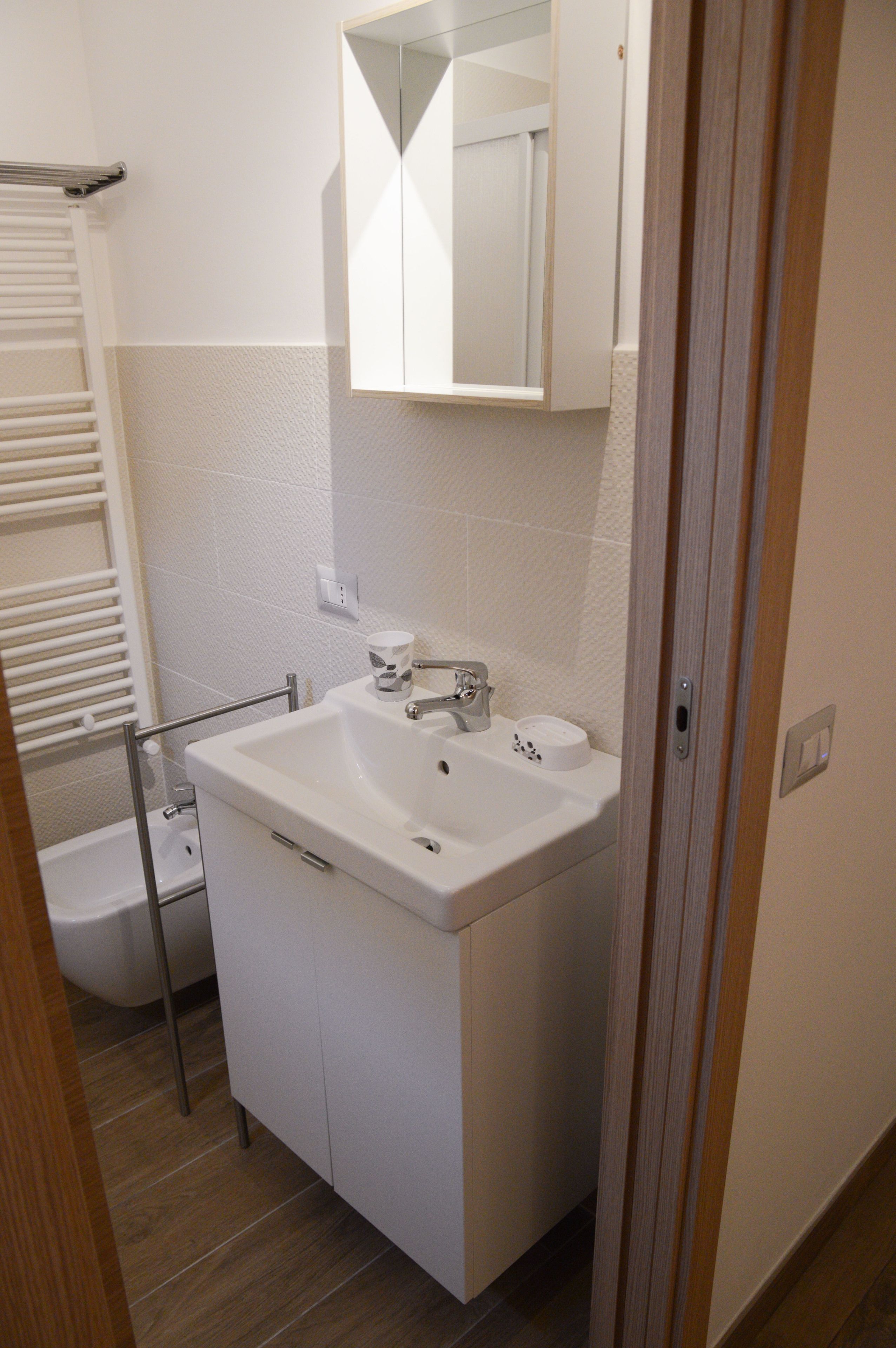 A bathroom with a white sink, mirror, and toilet.