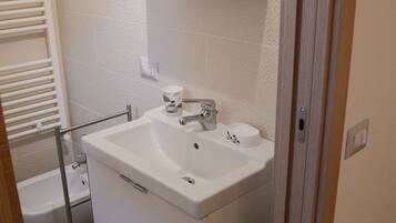 A bathroom with a white sink, mirror, and toilet.