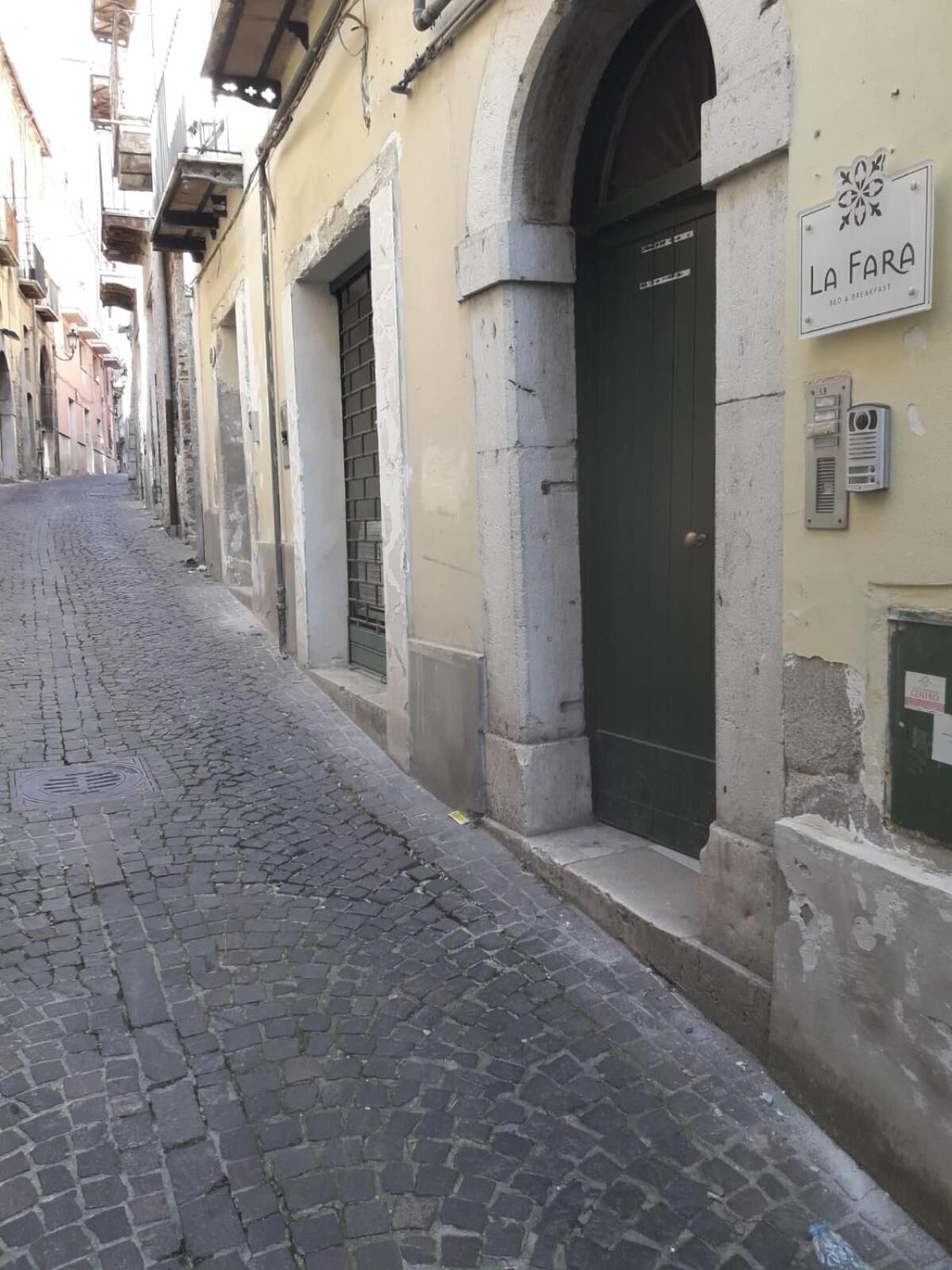 Una stretta strada acciottolata con un edificio che presenta un cartello con la scritta 'La Fara Bed & Breakfast'.