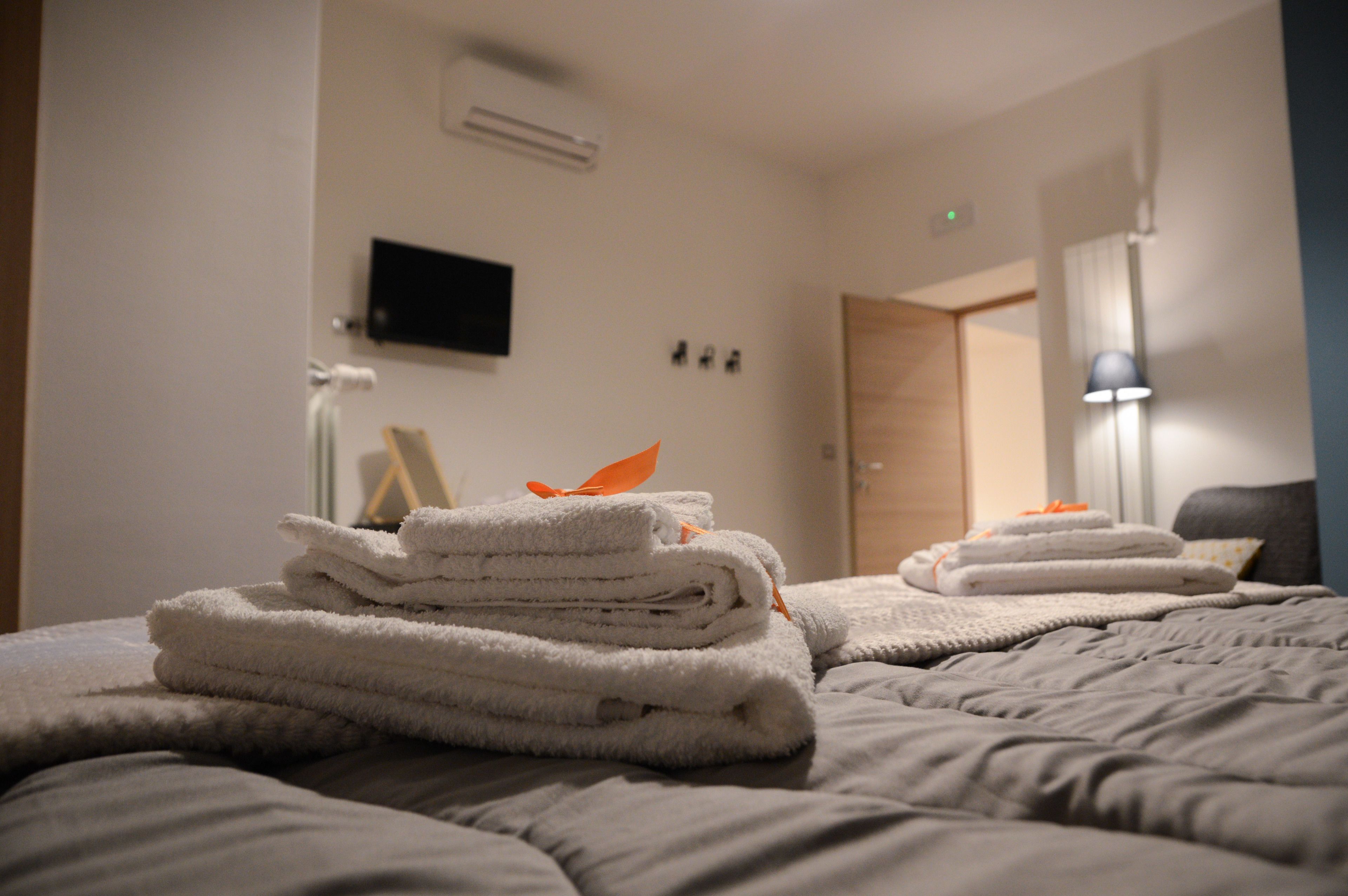 A neatly made bed with folded towels and a lamp in the corner.