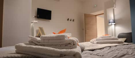 A neatly made bed with folded towels and a lamp in the corner.
