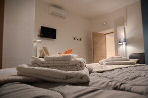 A neatly made bed with folded towels and a lamp in the corner.