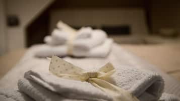 A neatly folded set of towels with a polka-dotted ribbon tied in the center, placed on a bed in a room with a sloped ceiling.