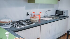 A modern kitchen with a gas stove, microwave, and a variety of food items on the counter. - La Fara B&B (Benevento)