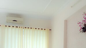 A hotel room with two beds, a wooden headboard, a nightstand with a lamp, and a wall-mounted air conditioner. - Quang Diep Hostel (Ho Chi Minh City)