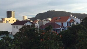 A residential area with houses, a hill with a cross, and a tall building in the background. - Quang Diep Hostel (Ho Chi Minh City)