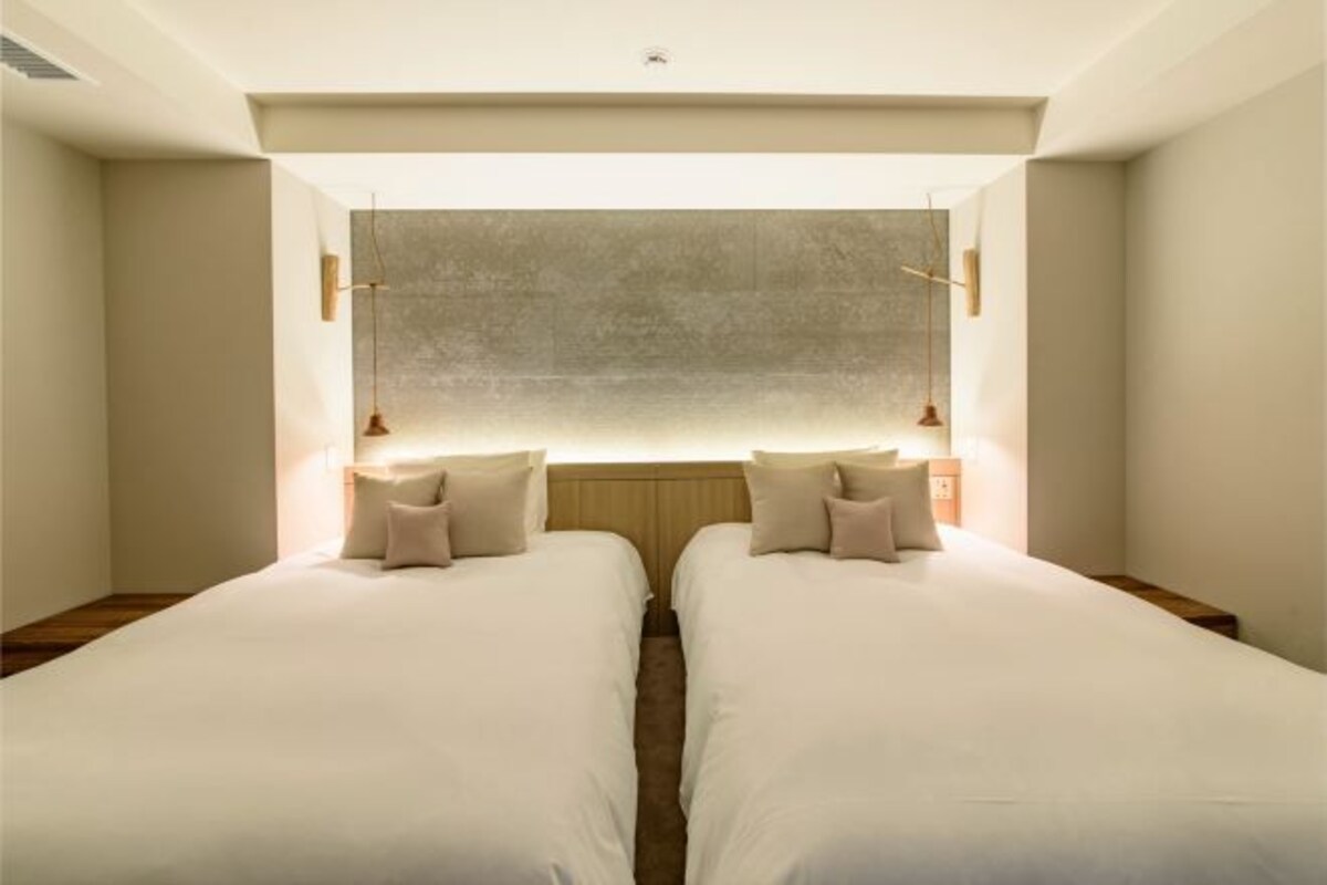 A double room with two beds, a large window, and a simple, modern design.