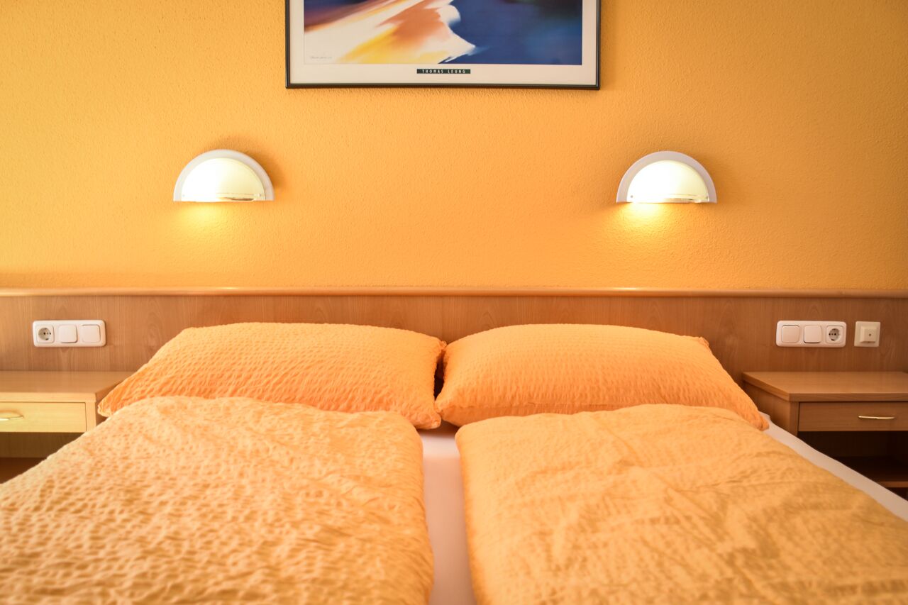 Een hotelkamer met een tweepersoonsbed, twee nachtkastjes en twee wandlampen.
