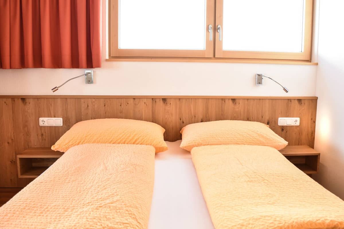 Una cama doble con cabecera de madera y dos mesitas de noche, cada una con una lámpara.