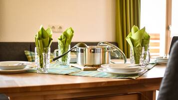 A dining table set with clear glassware, green napkins, and a stainless steel pot.