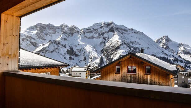 Una cabaña de madera con vistas a montañas nevadas.
