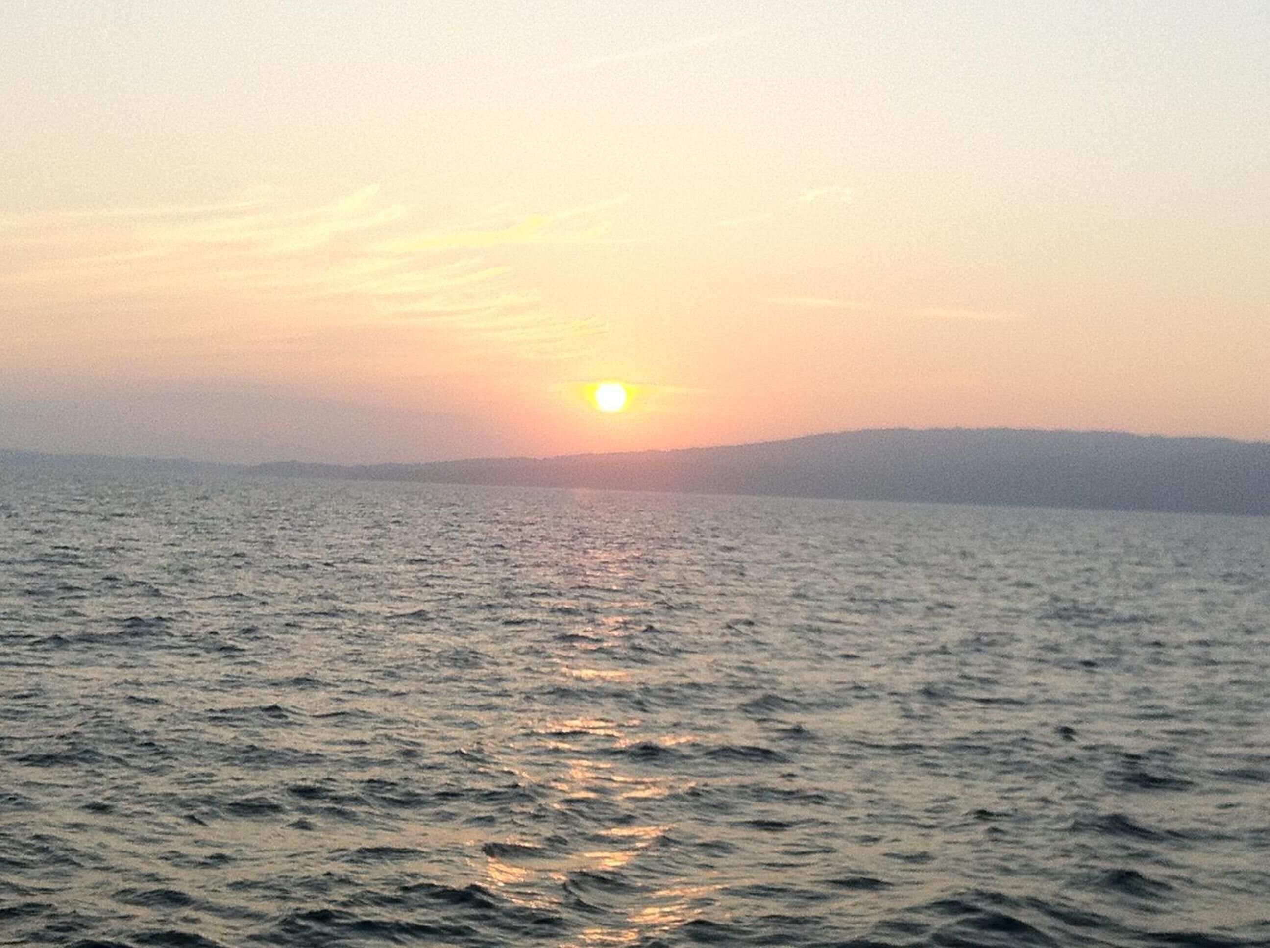 Un atardecer sobre un cuerpo de agua con tierras lejanas.