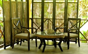 A seating area with two chairs and a round table, surrounded by bamboo screens.